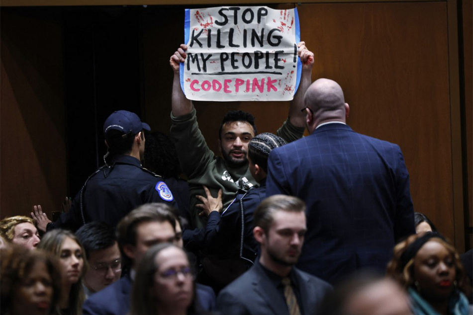 Palestinian-American activist Moataz Salim raises a sign reading "Stop Killing My People" as he disrupts a Senate Intelligence Committee hearing.