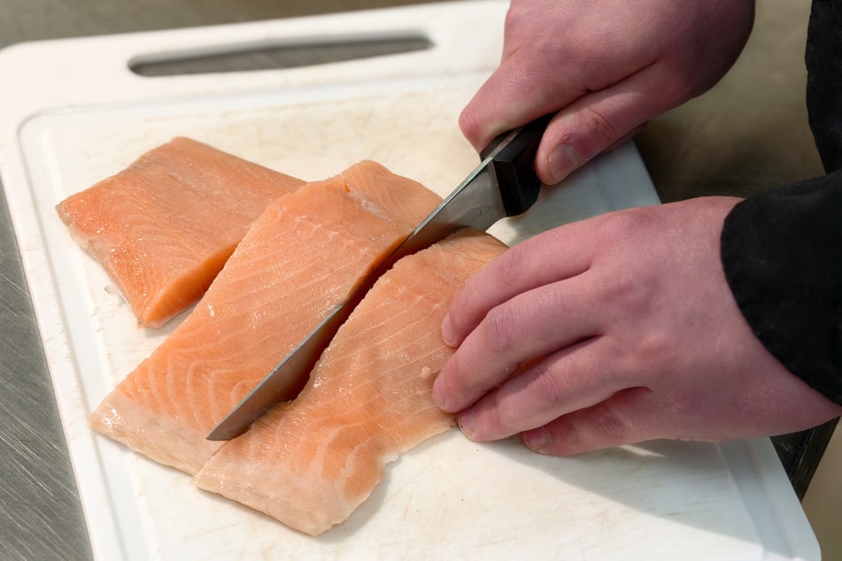 Frischer Lachs wird vor der Verarbeitung in Portionen geschnitten.