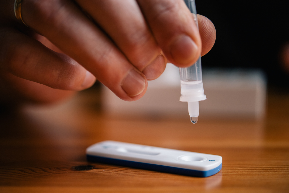 Ein Mann träufelt eine Lösung auf eine Testkassette, die von Covid-19 verursachte Antigene nachweisen kann.