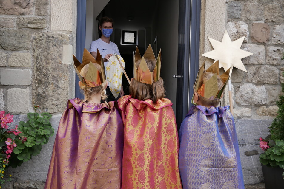 Kreativität in Corona-Zeiten: Mittels selbst gebasteltem Kescher nehmen drei Sternsinger eine Spende entgegen.