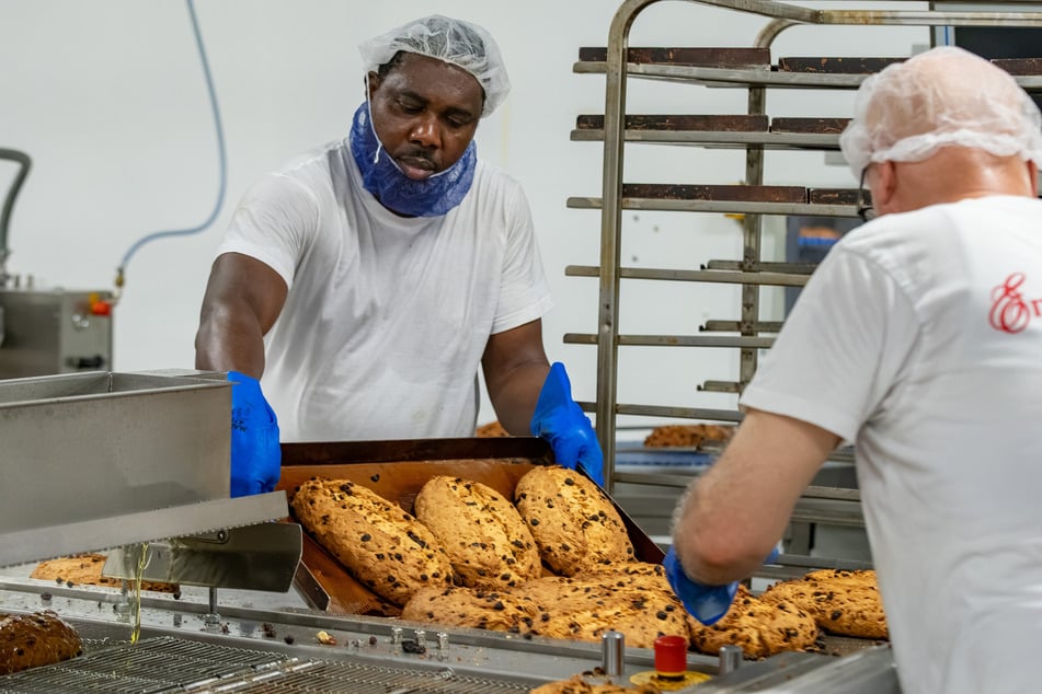 Und jetzt abkühlen lassen: Mitarbeiter holen die noch heißen Stollen vom Blech.