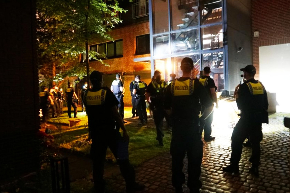 Zahlreiche Einsatzkräfte der Polizei stehen vor dem Mehrfamilienhaus, in dem die Swinger-Party stattfand.