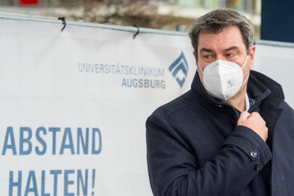 Markus Söder (53, CSU), Ministerpräsident von Bayern, steht mit einer Maske vor der Uniklinik vor dem Schriftzug "Abstand halten".