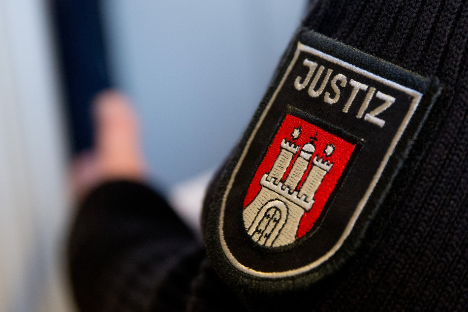 Ein Justizbeamter steht in einem Gerichtsaal des Landgerichts Hamburg. Dort muss sich erneut ein 26-Jähriger verantworten, der mehrere Angriffe auf seine schwangere Freundin organisiert haben soll. (Symbolfoto)