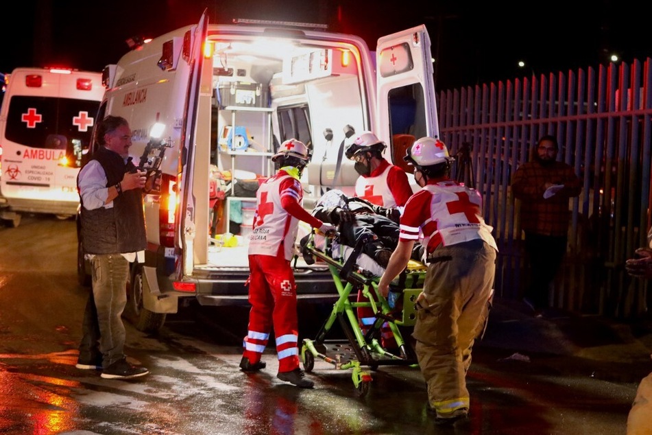 Paramedics carry an injured person following a fire that killed more than three dozen migrants in Ciudad Juarez.