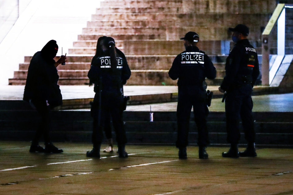 Polizeibeamte machen junge Frauen darauf aufmerksam, dass ab 23 Uhr der Konsum von Alkohol auf dem Schlossplatz in Stuttgart untersagt ist.