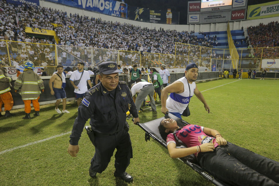 Ein verletzter Fan wird vom Spielfeld des Cuscatlan-Stadions in San Salvador, El Salvador, getragen.