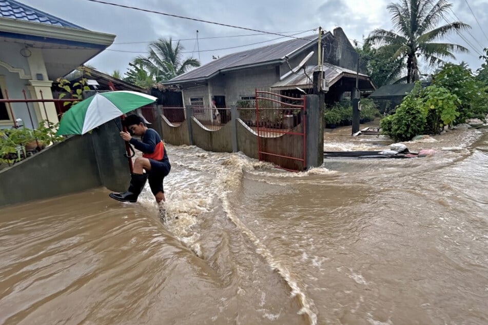 Ein Mann watet in der Stadt Propseridad in der Provinz Agusan del Sur im Süden der Insel Mindanao durch die von schweren Regenfällen verursachten Überschwemmungen.
