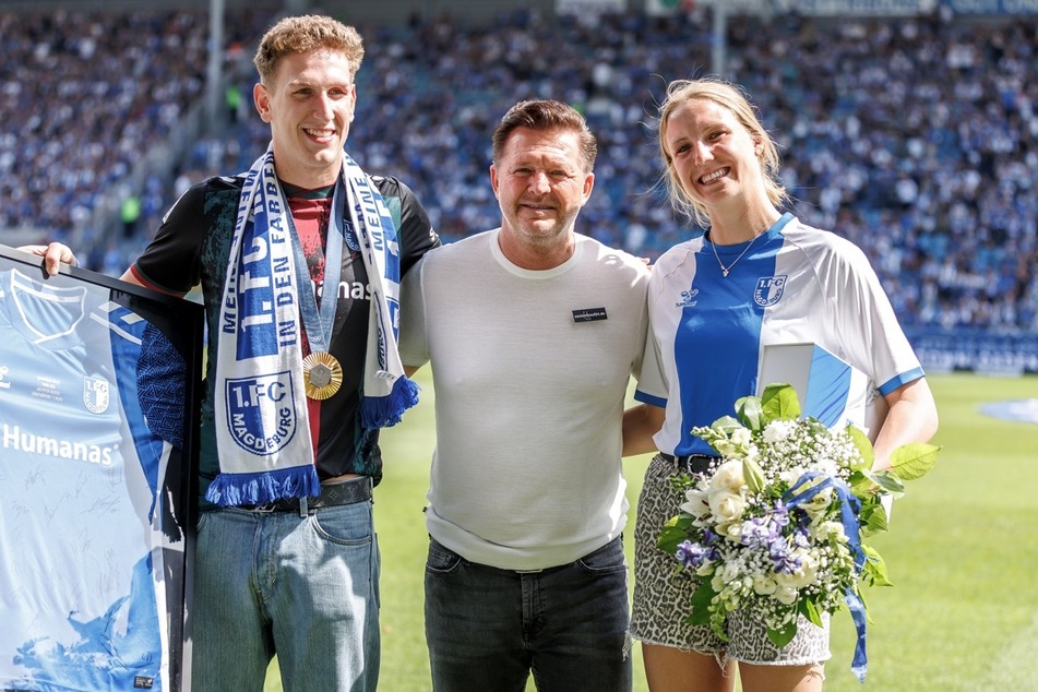 FCM-Trainer Christian Titz (53, M.) ehrte die Olympia-Schwimmer Lukas Märtens (22, l.) und Isabel Gose (22) mit einem von den Spielern unterschriebenen Trikot und Blumen in der Avnet Arena.