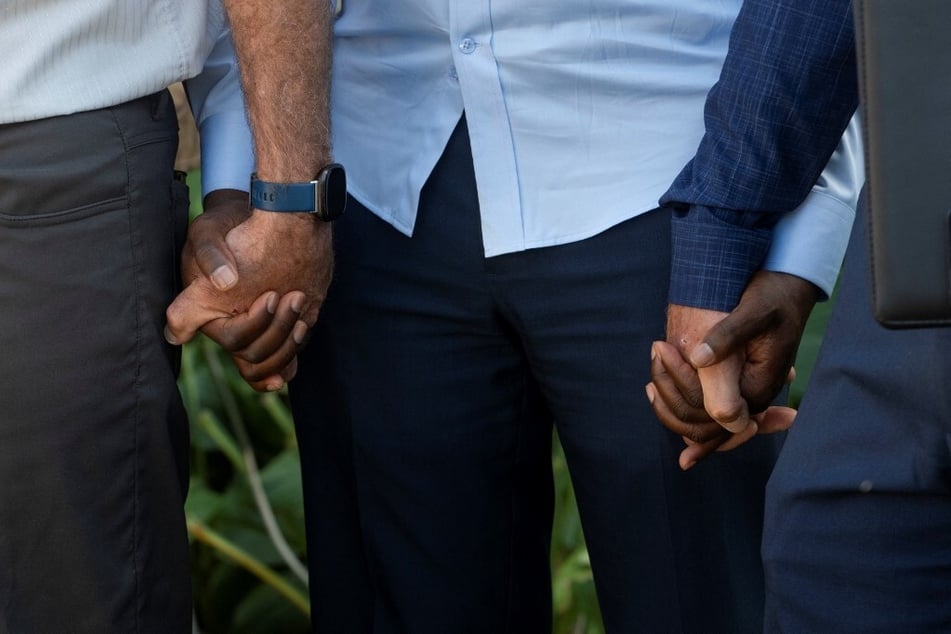 Vilés Dorsainvil (c.) holds hands with pastors during a prayer at the end of a press conference in Springfield, Ohio.