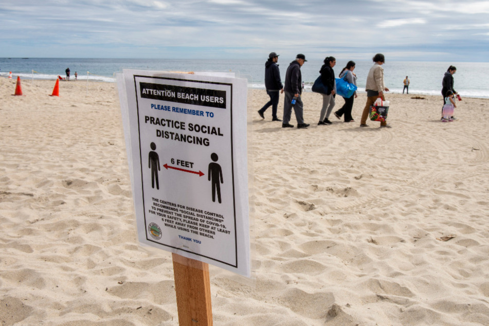 Schilder am Hauptstrand erinnern Strandbesucher daran, wegen der Corona-Krise den vorgeschriebenen Mindestabstand von sechs Fuß (etwa 1,8 Meter) zu halten.