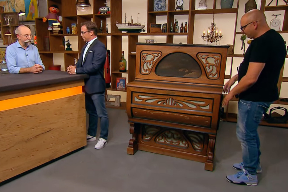 Unternehmensberater Marcel aus Köln (2.v.l.) möchte bei "Bares für Rares" einen alten Piano-Automaten aus der Kaiserzeit verkaufen.