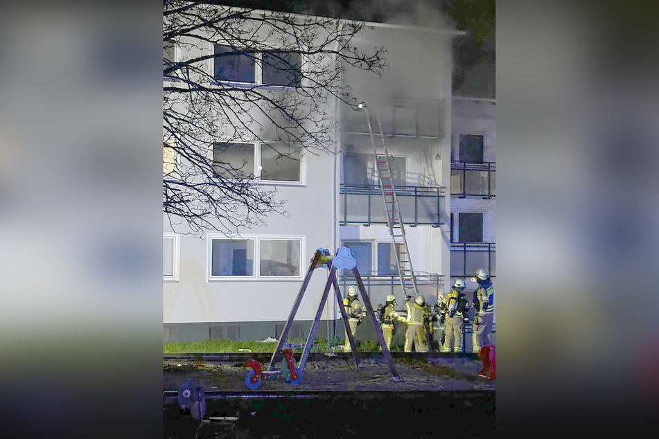 Einsatzkräfte der Feuerwehr dringen über Leitern in das verrauchte Gebäude ein.