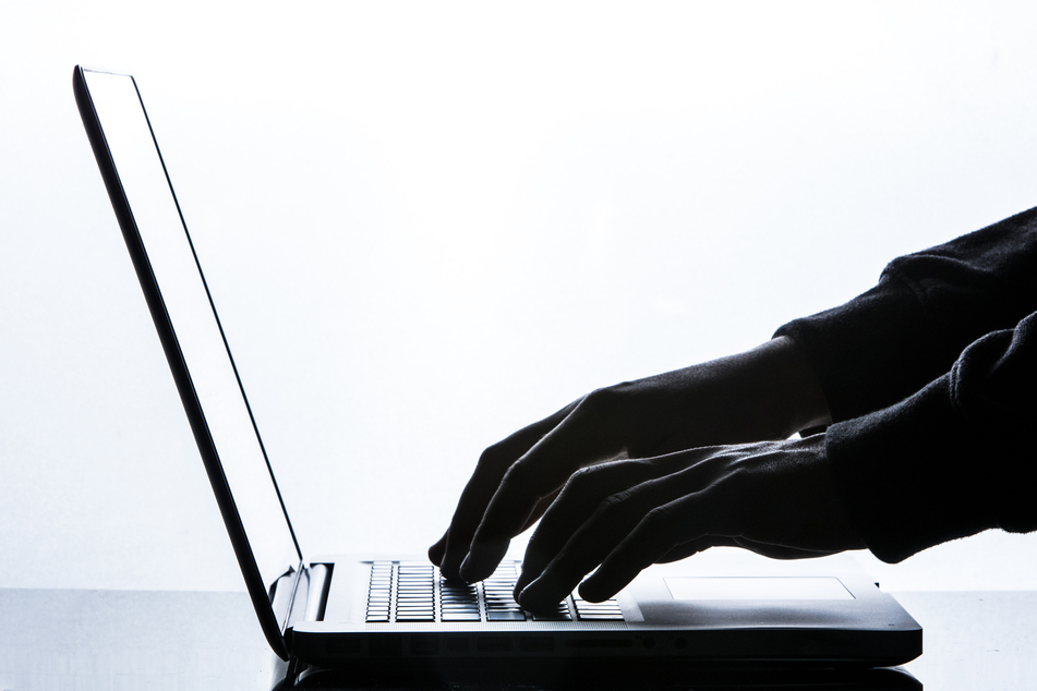 Ein Mann tippt auf einer Tastatur eines Laptops.