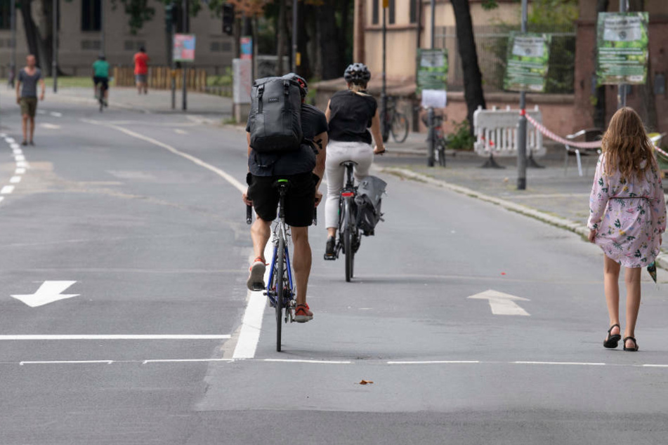 Radfahrer und Fußgänger nutzen die Fahrbahn am Mainkai in Höhe des Römerbergs. In der übernächsten Woche soll die Sperrung des Mainkai für den Autoverkehr aufgehoben werden.
