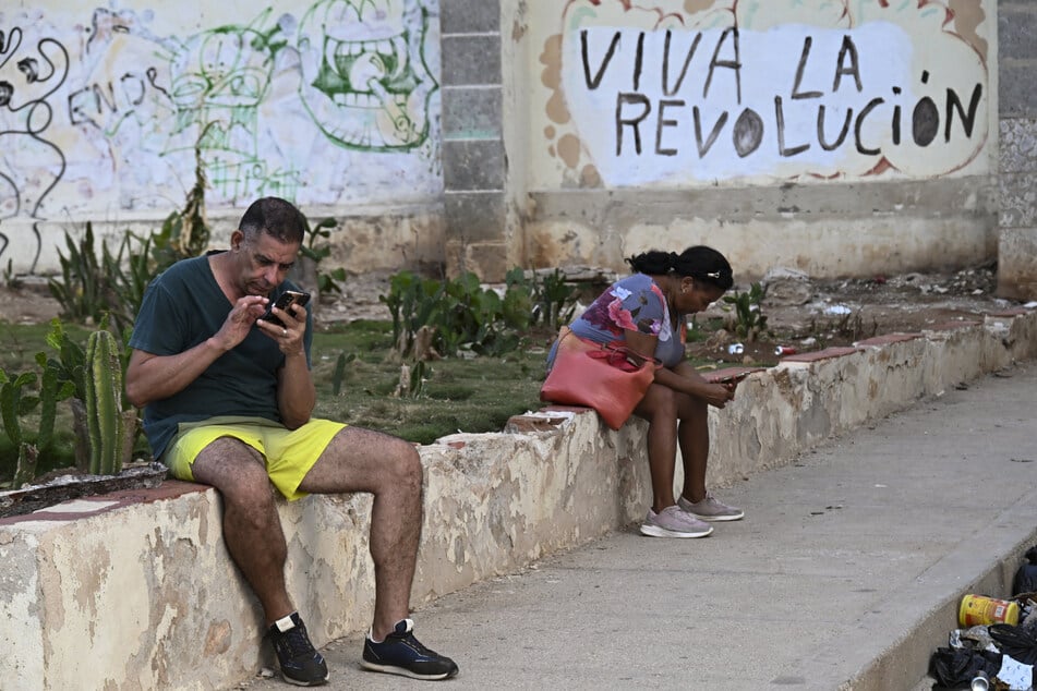 People look at their phones on a street during a blackout in Havana, Cuba, on August 1, 2026.