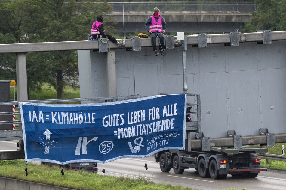 Klimaaktivisten demonstrieren mit einem Plakat auf der A9 nahe der Allianz Arena gegen die IAA.