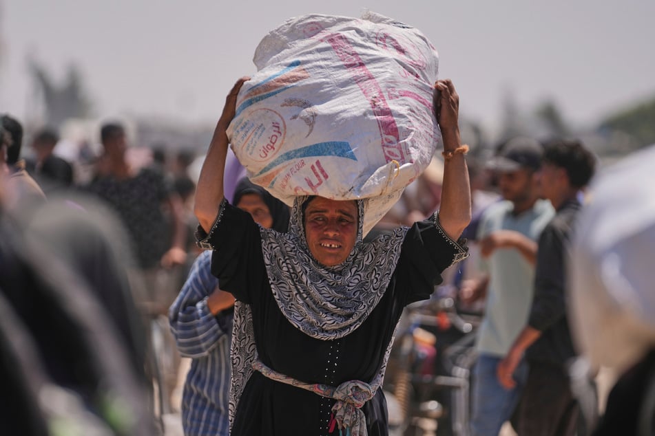 Rafah: Eine palästinensische Frau trägt eine Tasche mit Lebensmitteln und humanitärer Hilfe, die von der Gaza Humanitarian Foundation, einer von den USA unterstützten Organisation, geliefert wurde.