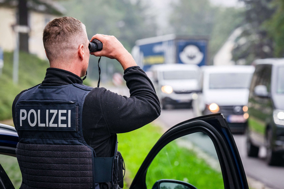 Ein Beamter der Bundespolizeiinspektion Chemnitz hält mit einem Fernglas an der B174 bei Hohndorf Ausschau nach Schleuserfahrzeugen.
