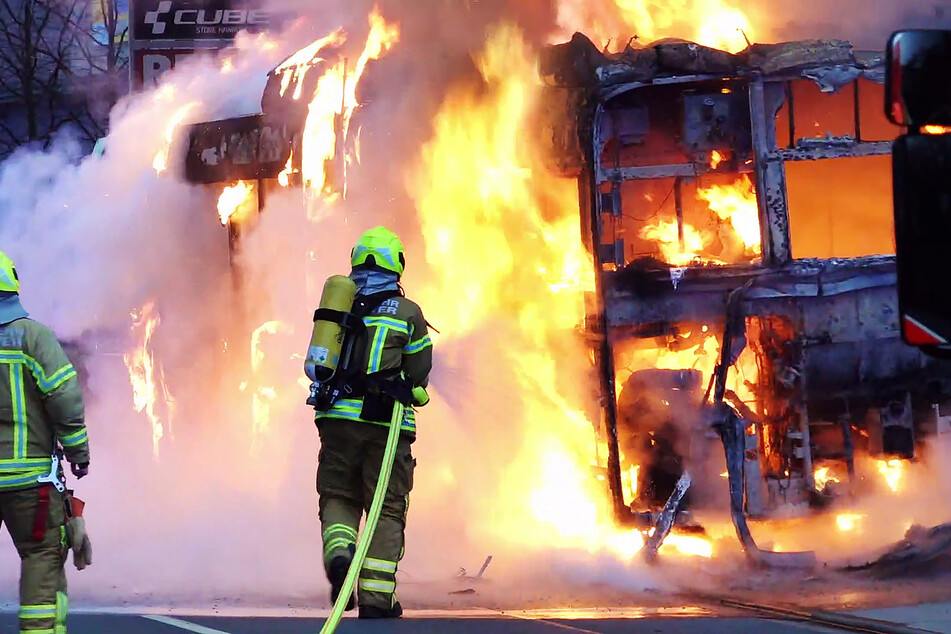 Feuerwehrkräfte löschen den brennenden Linienbus.