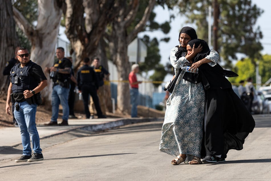 Two women react as they leave a reunification center following the shooting at the Islamic Center of San Diego, California, on May 18, 2026.
