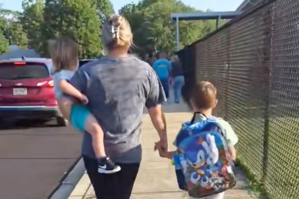 Taylor Isbell (29) hält ihren Sohn zu Beginn des Videos an der Hand, als sie auf die Grundschule zugehen.