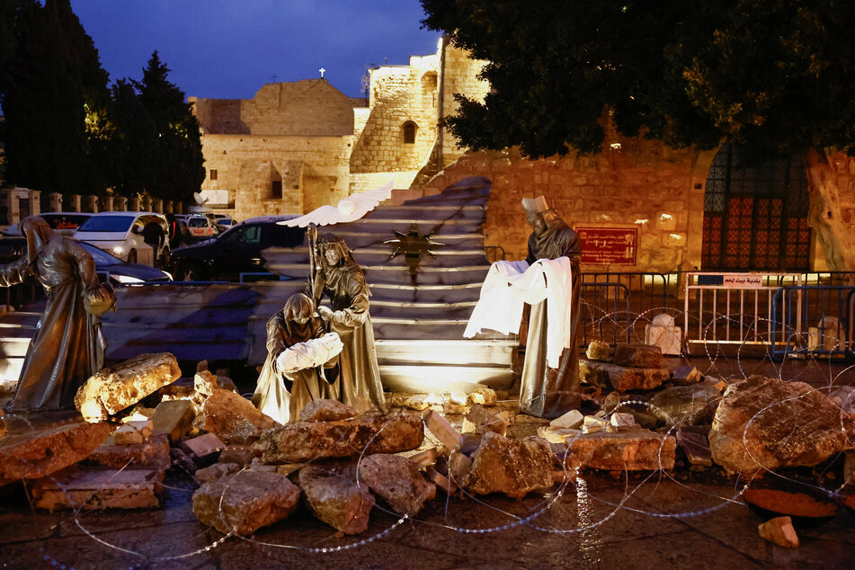 A Christmas installation of a grotto with figures standing amid rubble surrounded by a razor wire, is displayed outside the Church of the Nativity, in support of Gaza, on Manger Square in Bethlehem, in the Israeli-occupied West Bank.