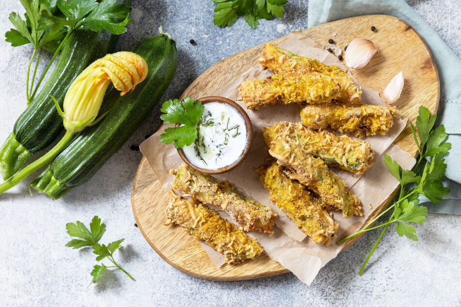 Zu den knusprigen Zucchini-Pommes passt ein Kräuterdip.