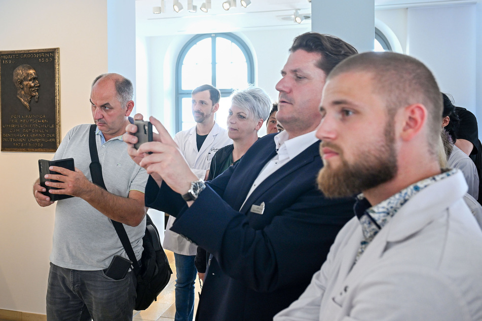 Besucher wie auch Uhrmacher verfolgen interessiert die Ingangsetzung der Kunstuhr.