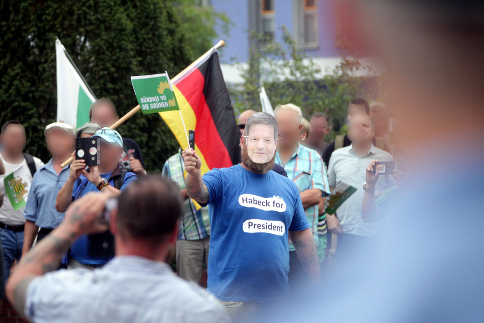 Ein Demonstrant mit einer Pappmaske vor seinem Gesicht - darauf das Abbild von Grünen-Politiker Robert Habeck (52) - bei einer Versammlung am 15. August 2022 in Heidenau unter dem Motto "Regierungsrücktritt jetzt" von Anhängern der Freien Sachsen.