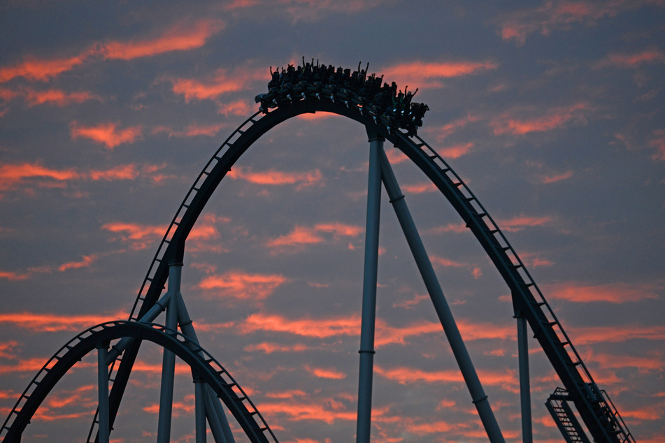 Besucher des Europa-Parks in Rust fahren in der Sonnenuntergangsstimmung mit der Achterbahn "Silverstar".