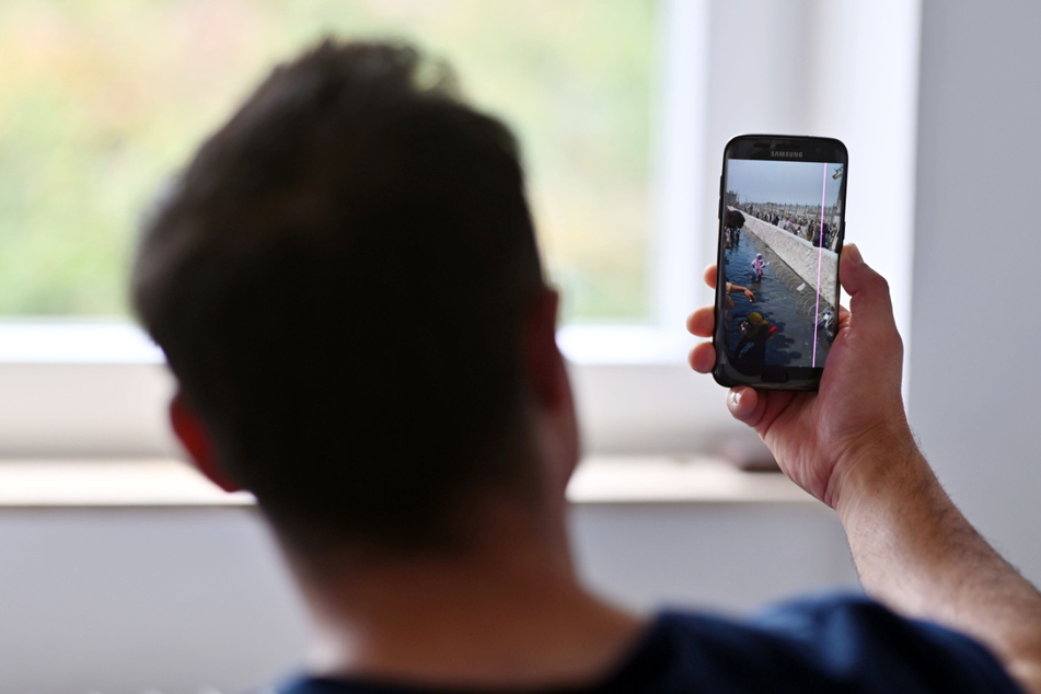 Der 29-Jährige zeigt auf einem Handy ein Foto, das er nach eigenen Angaben bei seiner Flucht zum Flughafen in Kabul gemacht hat.