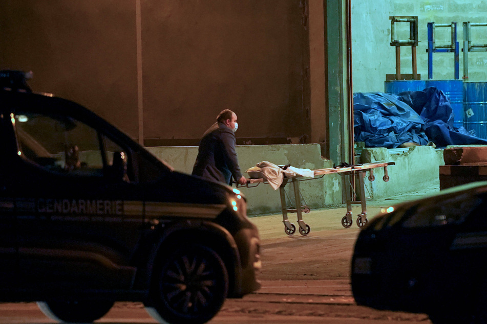 A man wheels a gurney into a warehouse in the Port of Calais, France, where it is believed the bodies of migrants are being transported after the tragedy.