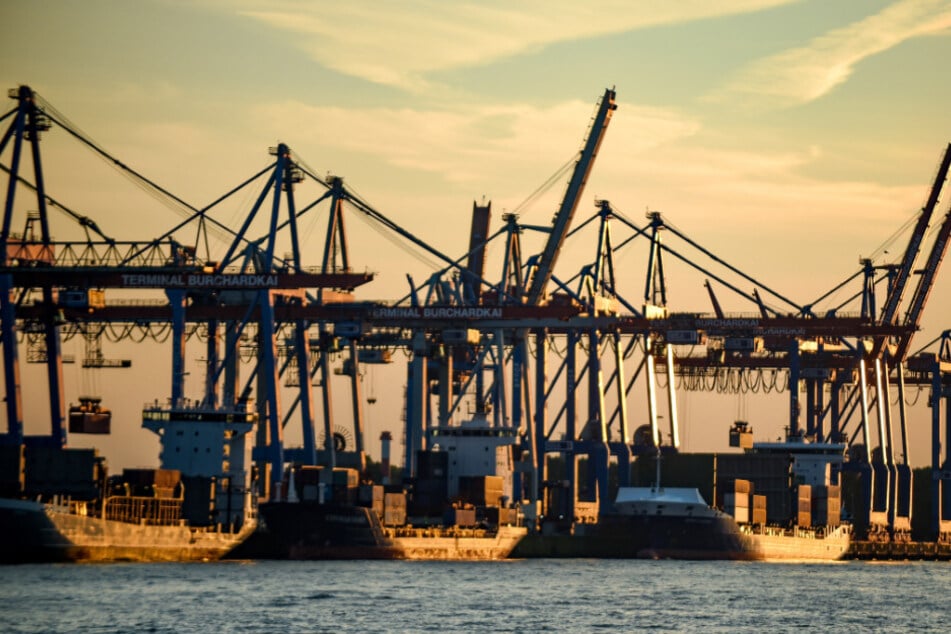 Containerschiffe werden im Hamburger Hafen bei untergehender Sonne abgefertigt.