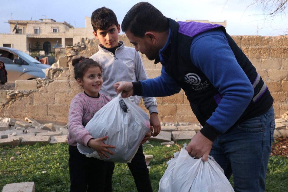 Ein Mitarbeiter der "arche noVa"-Partnerorganisation "Bonyan" verteilt Hilfspakete an syrische Kinder.