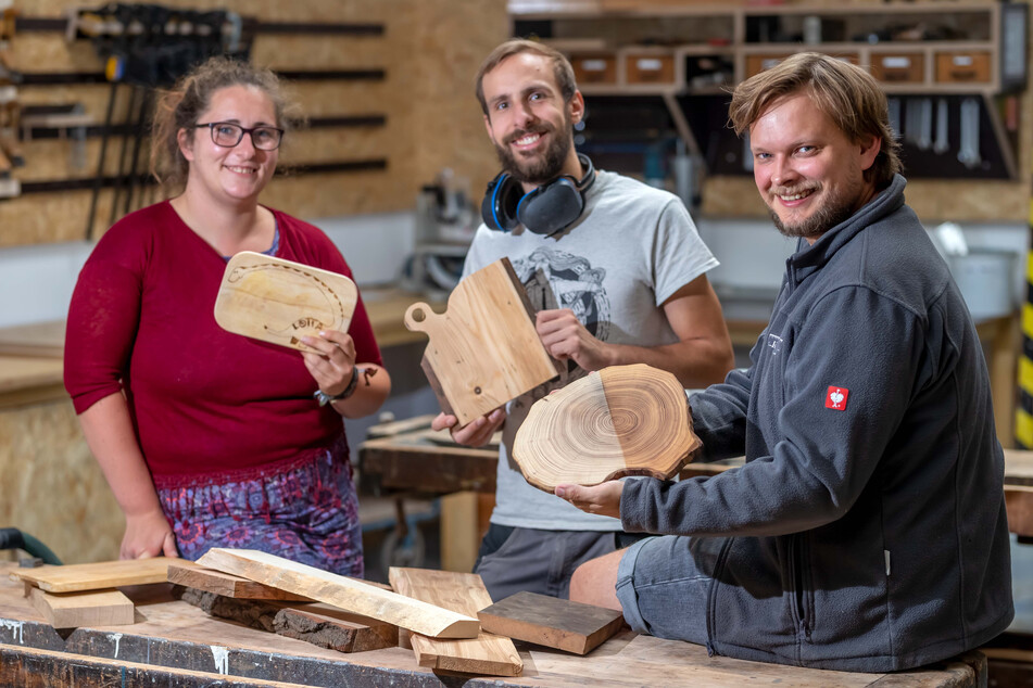 Caroline Kügler (29), Jonas Titus Kerber (28) und Philipp Salzmann (32) vom Holzkombinat zeigen Frühstücksbrettchen aus Holz.