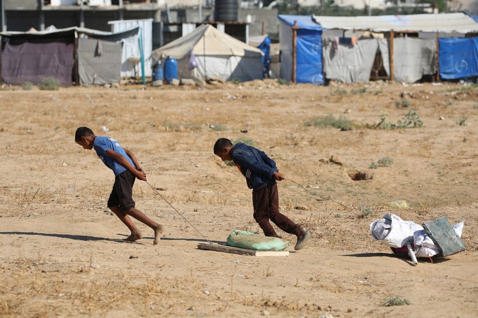 Palestinian boys drag bags of items salvaged from a garbage waste dump in the Al-Bureij camp in the central Gaza Strip on July 7, 2025.