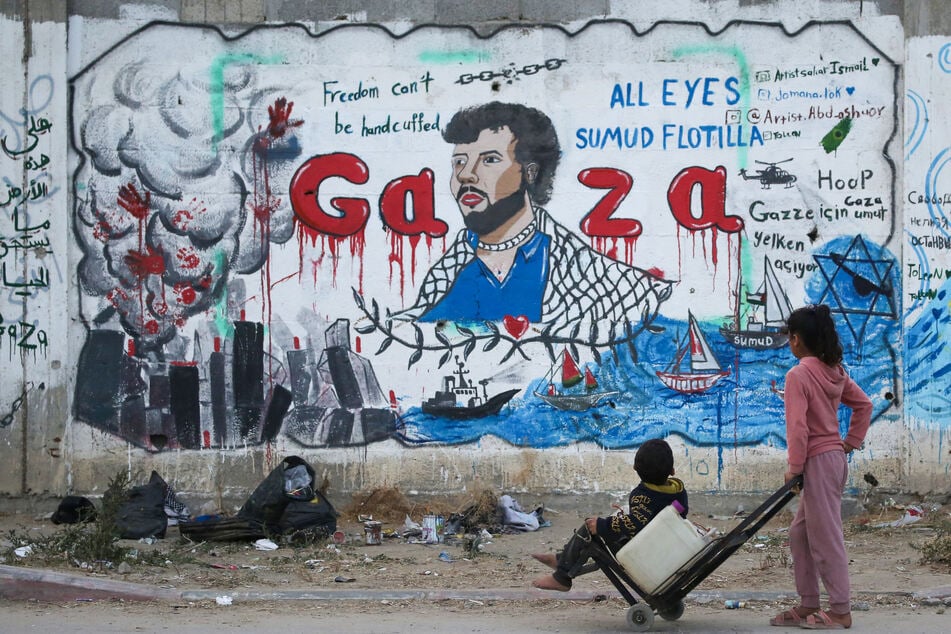Palestinian children look at a mural depicting Israel's interception of ships participating in the Global Sumud Flotilla in Nuseirat in the central Gaza Strip on May 19, 2026.