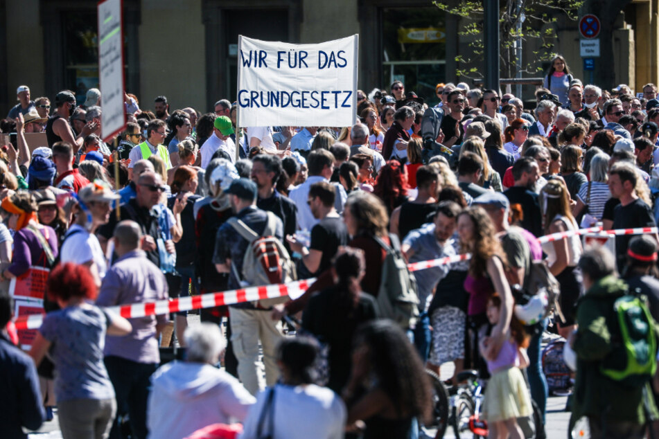 "Wir für das Grundgesetz" steht auf einem Transparent geschrieben, das Teilnehmer der dritten Demonstration der "Querdenken"-Initiative auf dem Stuttgarter Schlossplatz in die Höhe halten.