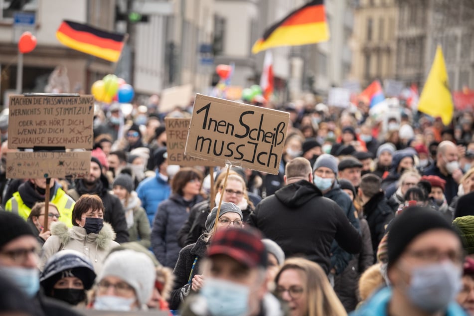 Eine Frau trägt ein Plakat mit der Aufschrift "1nen Scheiß muss ich" bei einer Demonstration von mehreren Tausend Menschen gegen Corona-Maßnahmen und Impfpflicht in der Frankfurter Innenstadt.