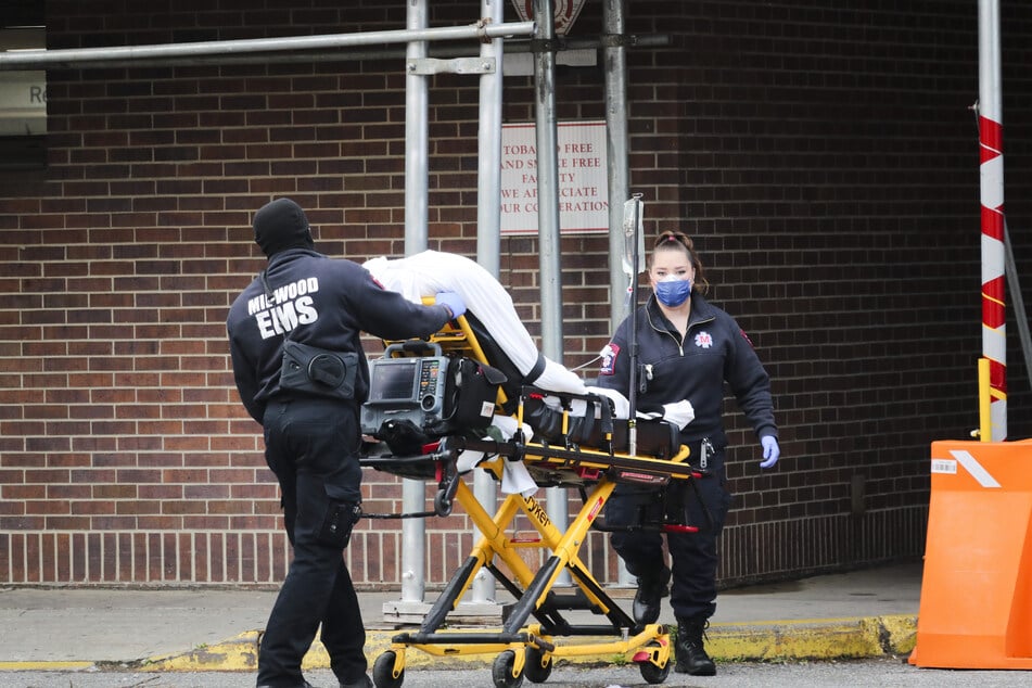 Mitarbeiter des Gesundheitswesens schieben einen Patienten in das Brooklyn Hospital Center in Brooklyn.