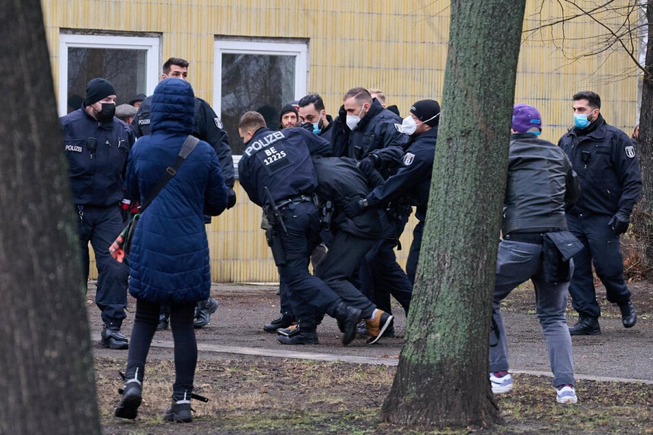 Ein Demonstrant wird von Polizisten neben der Karl-Marx-Allee festgesetzt.