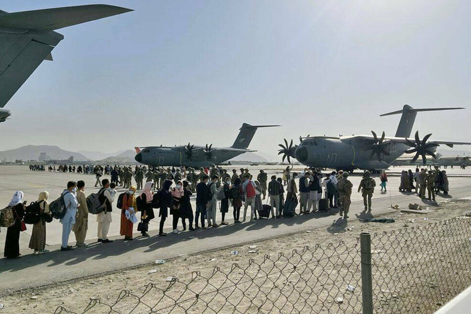 People wait to board airplanes out of Kabul following the Taliban takeover.