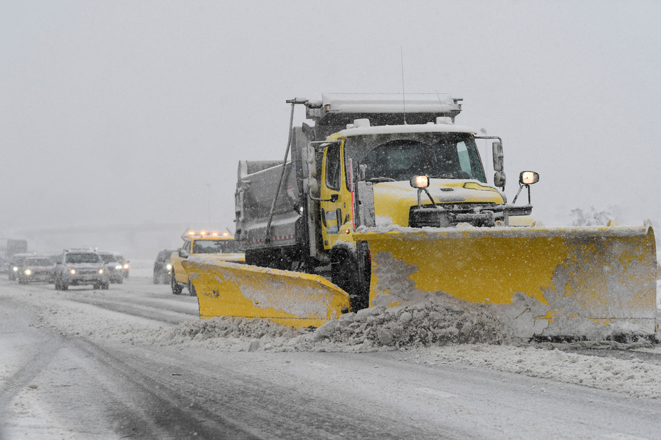 A snow plow clear the road in Massachusetts, with air traffic also affected by weather conditions.