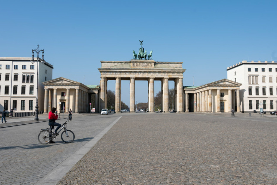 Ein Radfahrer steht vor dem Brandenburger Tor. An dem Touristen-Hotspot sind trotz des guten Wetters fast keine Besucher.