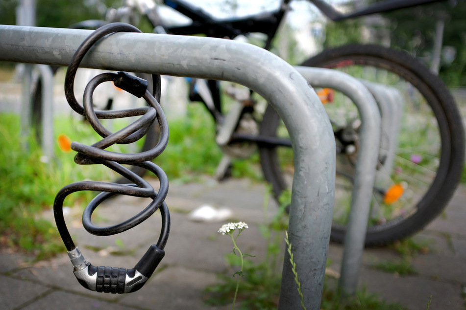 Ein Kabelschloss hängt an einem Fahrradständer. (Symbolbild)
