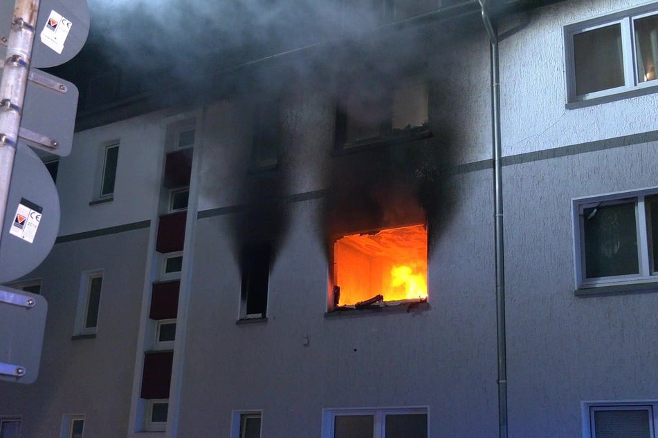 Flammen schlagen aus einem Fenster der brennenden Wohnung.