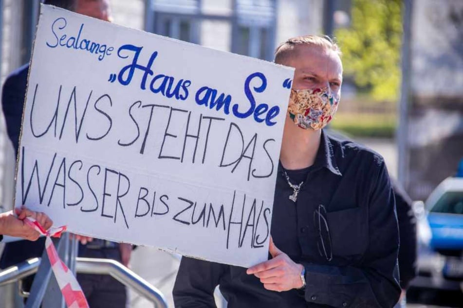 Ein Demonstrant trägt bei einer Demonstration für finanzielle Hilfen und Steuererleichterungen zur Rettung der geschlossenen Betriebe im Tourismusgewerbe einen Mundschutz und ein Schild mit der Aufschrift "Sealounge Haus am See - Uns steht das Wasser bis zum Hals".