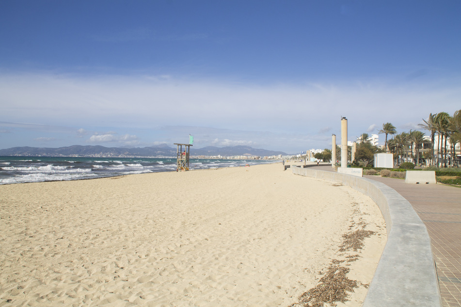 Ein Bademeister (l) arbeitet am leeren Strand von Palma. Die Corona-Krise hat die deutsche Reisebranche weiter fest im Griff.