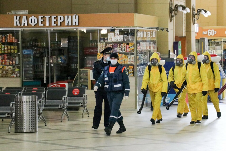 Mitarbeiter der Stadt in gelben Schutzanzügen desinfizieren den Bahnhof Kiewski (Kiew) in Moskau.